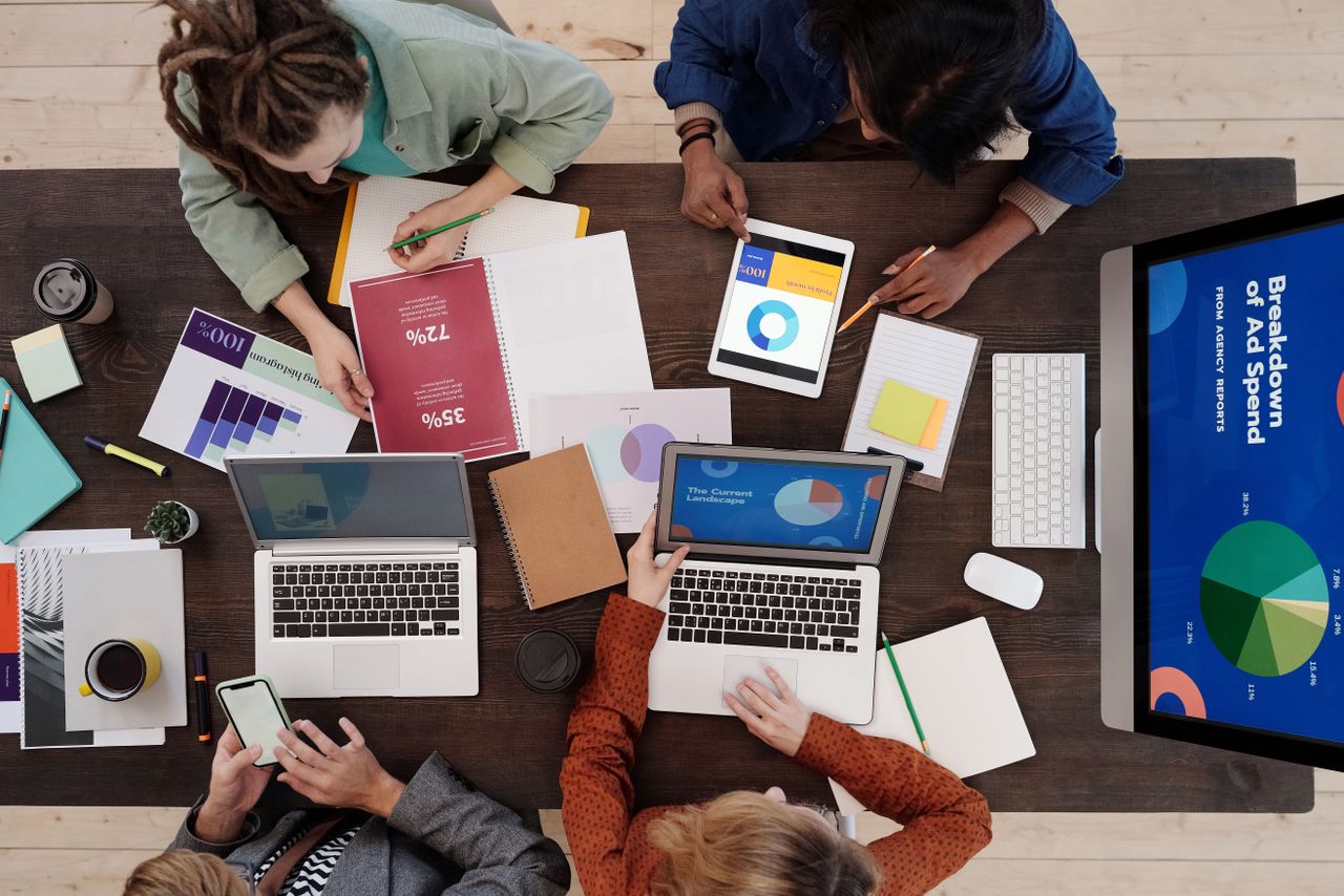 Une équipe variée travaillant ensemble sur des stratégies de marketing digital autour d’une table, avec des ordinateurs portables et des tablettes.